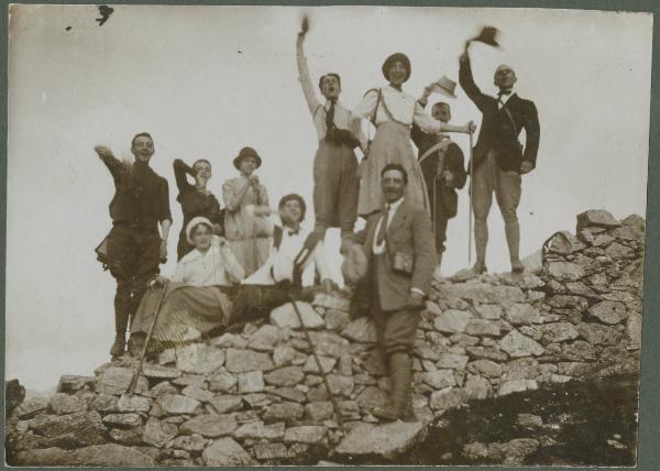 Ritratto di gruppo - Antonio Boschi con uomini e donne su un muretto - Braccia alzate - Esterno - Montagna - Escursione
