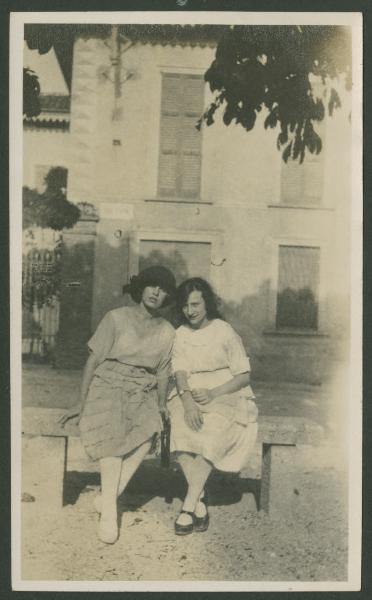 Ritratto femminile - Marieda Di Stefano con altra ragazza sedute su una panchina - Esterno - Strada - Edificio