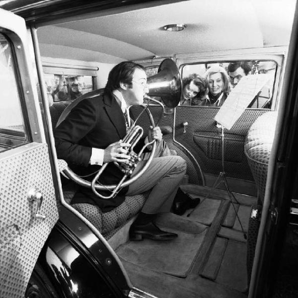Musicista suona il corno all'interno di un'automobile