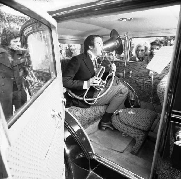 Musicista suona il corno all'interno di un'automobile