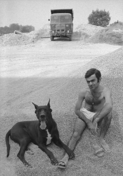 Ritratto maschile - giovane - modello che posa in costume da bagno con cane al guinzaglio