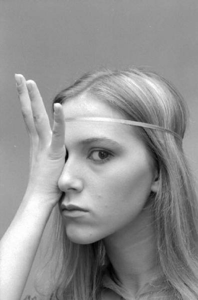 Ritratto femminile - primo piano di giovane modella con la mano sinistra appoggiata sul volto
