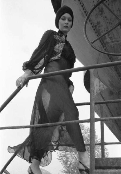 Ritratto femminile - giovane - modella che sale una scaletta e indossa un abito lungo e turbante in testa
