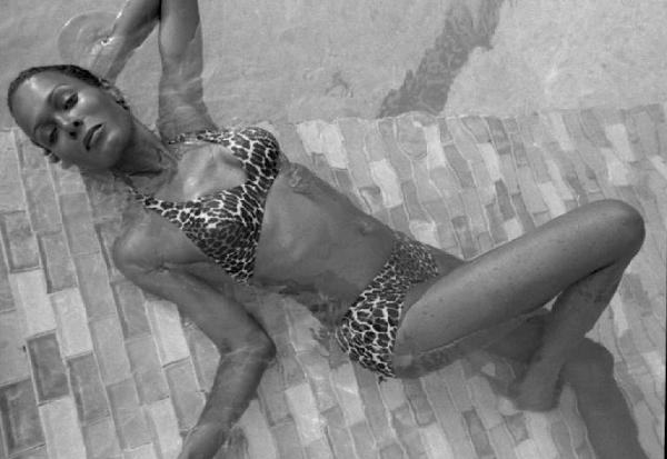 Ritratto femminile - giovane - modella di colore, immersa in una piscina, che indossa un bikini maculato. Ajita