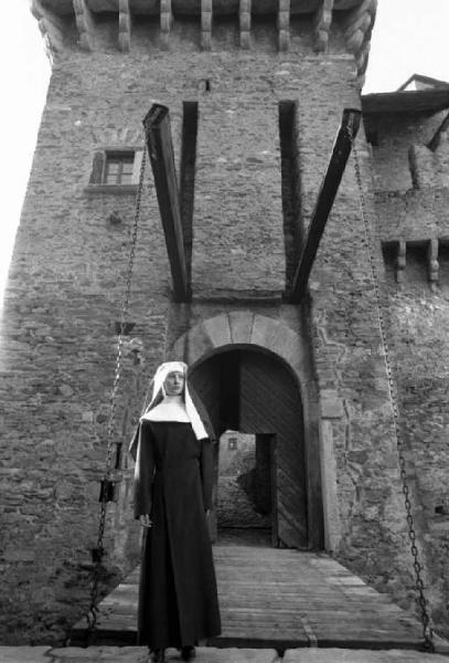 Ritratto femminile - giovane - modella travestita da suora posa di fronte al ponte levatoio di un castello. Lucy