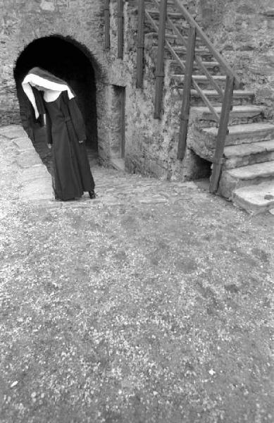 Ritratto femminile - giovane - modella travestita da suora posa presso l'ingresso di un castello. Lucy