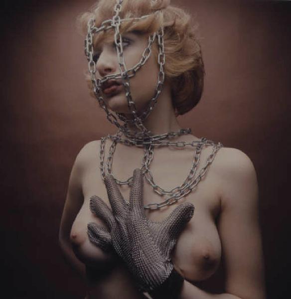 Ritratto femminile - modella in topless con catena sul volto e guanto in maglia di ferro