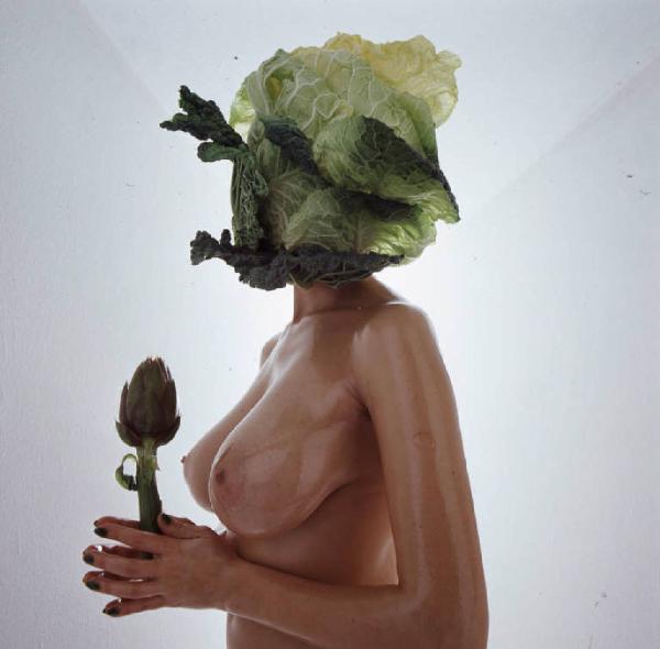 Nudo in studio - fotomodella con pianta di insalata sul viso - primo piano