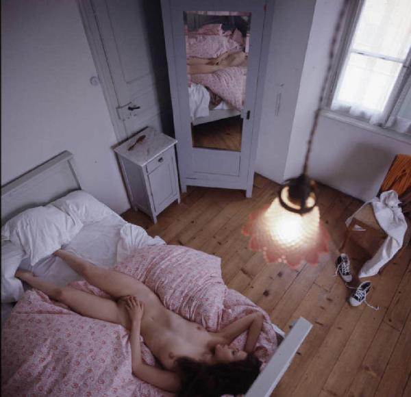 Ritratto femminile - modella nuda su un letto in una stanza, ripresa dall'alto