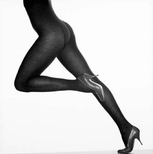 Gambe femminili in studio, con sfondo bianco e calza di nylon nera indosso