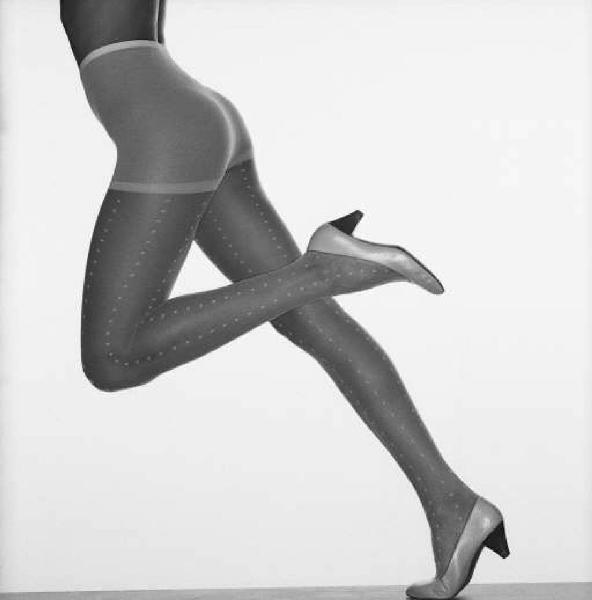 Gambe femminili in studio, con sfondo bianco e calza di nylon bianca indosso