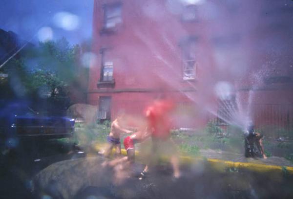 New York. Ragazzi giocano con l'acqua di un idrante lungo la strada