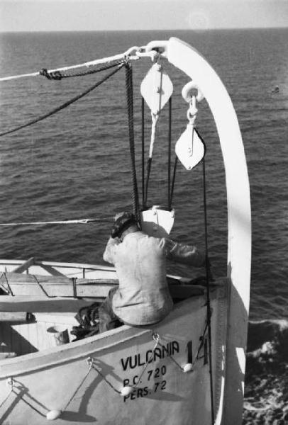 Viaggio verso l'Africa. A bordo del piroscafo "Vulcania" in navigazione, marinaio seduto di spalle in una scialuppa di salvataggio