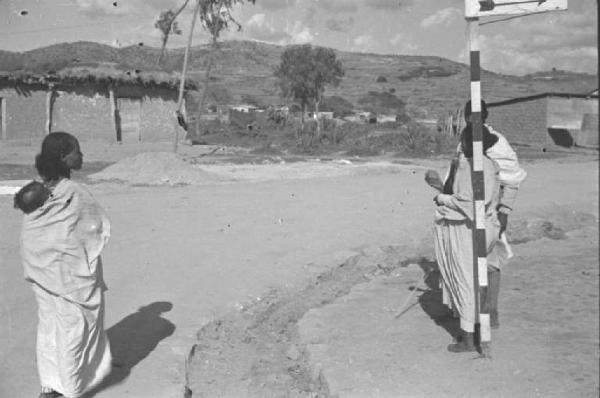Viaggio in Africa. Donna indigena con bambino sulla schiena cammina lungo una strada sterrata