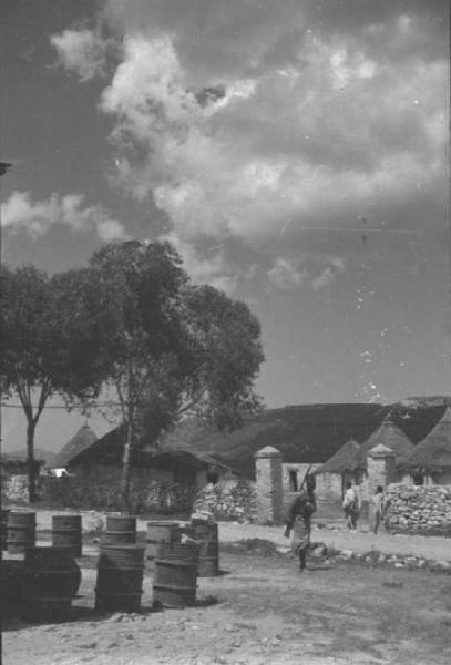 Viaggio in Africa. Villaggio - bidoni metallici e militare indigeno - sullo sfondo capanne con tetto di paglia