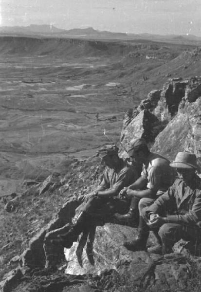 Viaggio in Africa. Ritratto di gruppo - tre militari seduti su uno sperone roccioso osservano il panorama