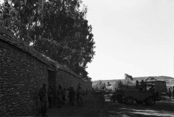 Viaggio in Africa. Militari italiani e indigeni nei pressi di un edificio in pietra