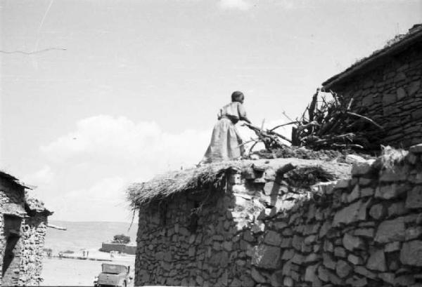 Viaggio in Africa. Macalle: scorcio dela villaggio, muretti a secco ed edifici in pietra con tetti di paglia. Indigeno sul tetto