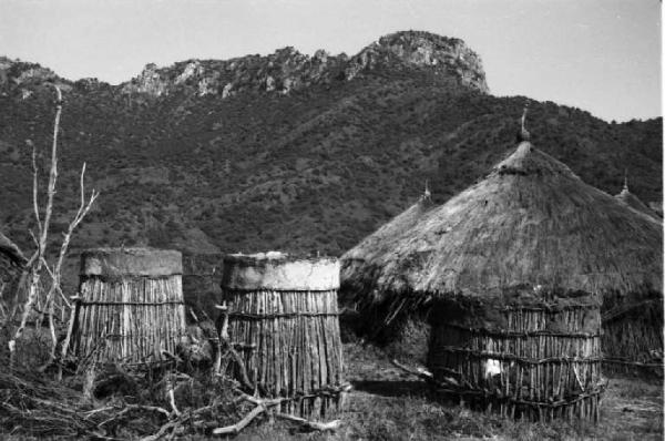 Viaggio in Africa. Paesaggio africano: villaggio di capanne tra la vegetazione. Colline in lontananza