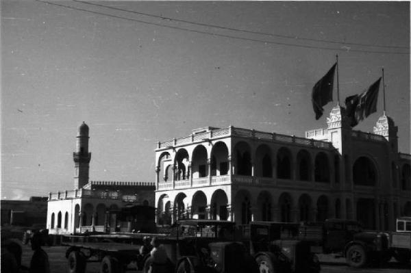 Viaggio in Africa. Massaua - edificio con doppio portico sovrapposto battente bandiera italiana - moschea con minareto