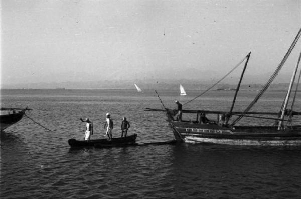 Viaggio in Africa. Massaua: scorcio del porto, imbarcazioni ancorate alla fonda e lancetta con tre portuali