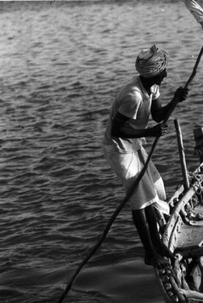 Viaggio in Africa. Massaua: portuale indigeno in piedi sul bordo di un'imbarcazione
