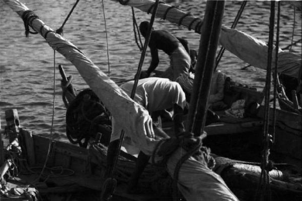 Viaggio in Africa. Massaua: due portuali indigeni al lavoro su imbarcazioni a vela