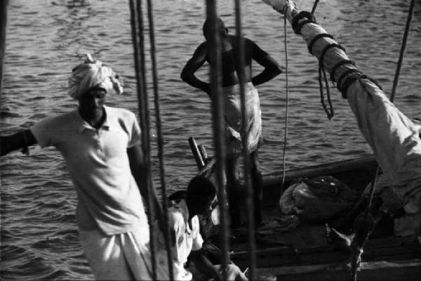 Viaggio in Africa. Massaua: due portuali indigeni al lavoro su imbarcazioni a vela