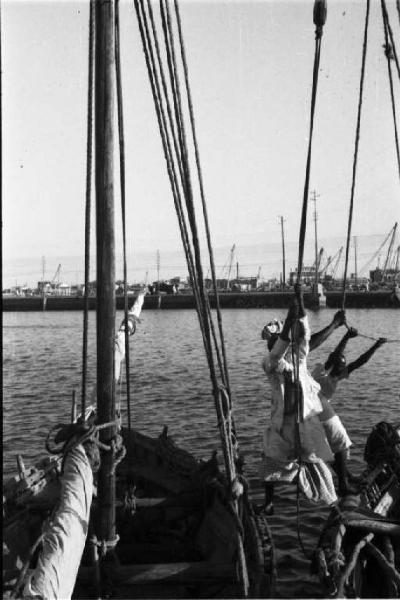 Viaggio in Africa. Massaua: scorcio del porto, portuali indigeni al lavoro su imbarcazioni a vela
