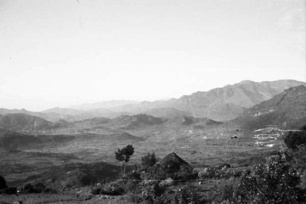 Viaggio in Africa. Paesaggio africano: villaggio di capanne seminascosto tra la vegetazione. In lontananza le colline