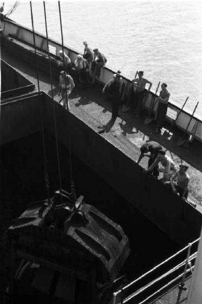 Porto di Savona. Operaio osservano le operazioni di carico del carbone nella stiva di una nave