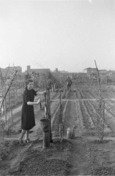 Periferia di Milano: orti di guerra a ridosso della città. Una donna pompa acqua per irrigare