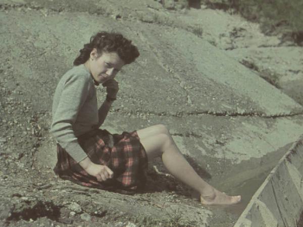 Ritratto femminile: giovane donna a piedi scalzi seduta a terra