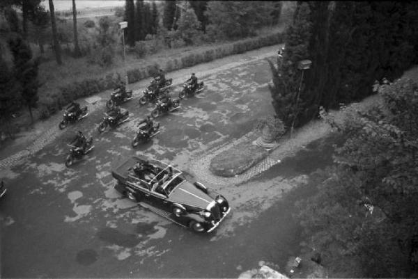 Patti di Roma. Ripresa dall'alto dell'automobile che trasporta Benito Mussolini e il "poglavnik" croato Ante Pavelic a villa Madama, mentre percorre un vialetto seguita da una scorta di motociclisti