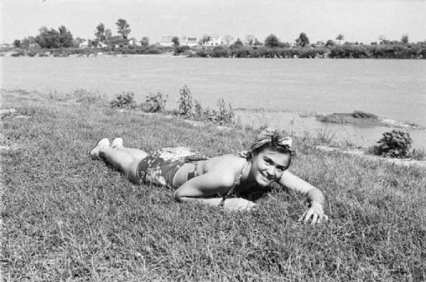 Viaggio in Jugoslavia. Zagabria: ritratto femminile, bagnante prende il sole sdraiata sui prati che costeggiano le rive del fiume Sava