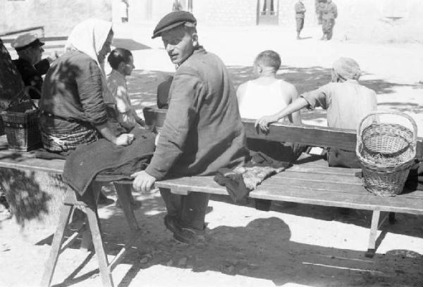 Viaggio in Jugoslavia. Un uomo e una donna seduti su un tavolaccio