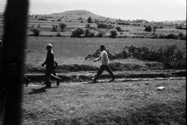 Viaggio in Jugoslavia. Verso Sebenico: coppia di passanti dal finestrino del treno - sullo sfondo la campagna