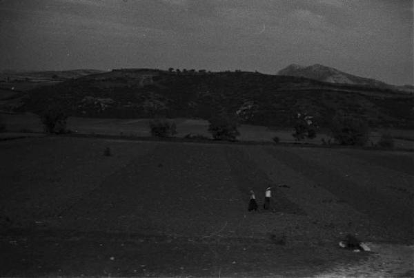 Viaggio in Jugoslavia.  Verso Sebenico: campagna nei pressi di Knin - scorcio del paesaggio dal finestrino del treno con coppia di contadini