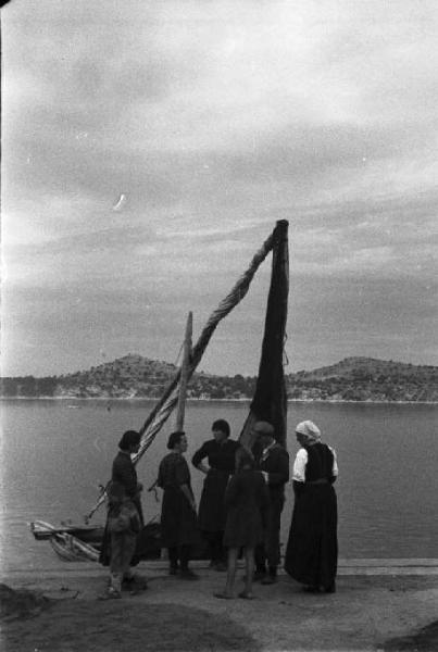 Viaggio in Jugoslavia. Sebenico: gruppo di abitanti discutono sul molo, nei pressi di un peschereccio