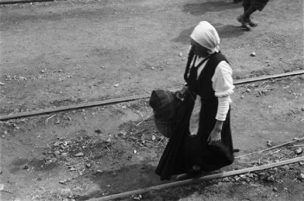 Viaggio in Jugoslavia. Sebenico: anziana donna con una valigia si incammina verso il treno