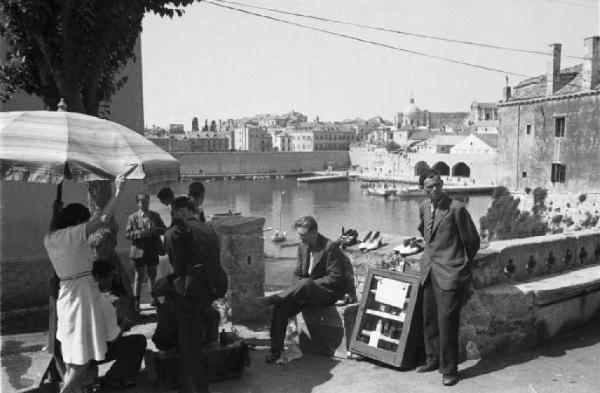 Viaggio in Jugoslavia. Dubrovnik (Ragusa): scene di vita quotidiana - gruppo di persone in riva al mare, sullo sfondo la città