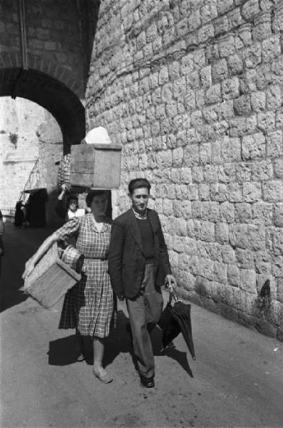 Viaggio in Jugoslavia. Dubrovnik (Ragusa): scene di vita quotidiana - coppia con donna che trasporta una cesta appoggiandola sulla testa