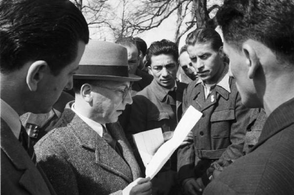 Internamento in Svizzera. Aarwangen, celebrazione per la commemorazione dei partigiani italiani: Leopoldo Gasparotto, Bruno e Fofi Vigorelli, Carlo Fabbri, Mario Greppi. Militari partecipanti alla messa assiepati attorno a un personaggio in borghese