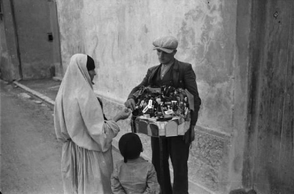 Viaggio in Jugoslavia. Mostar: scene di vita quotidiana - scorcio dall'alto: venditore ambulante vende la sua merce a una donna con bambino