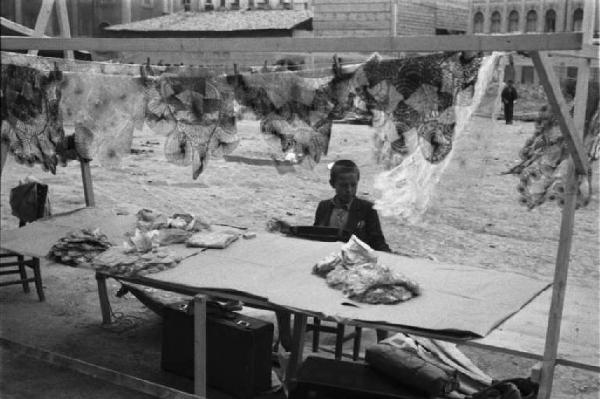 Viaggio in Jugoslavia. Sarajevo: scorcio di una bancarella nella piazza della cattedrale durante il mercato - in primo piano un giovane fanciullo che gestisce la bancarella