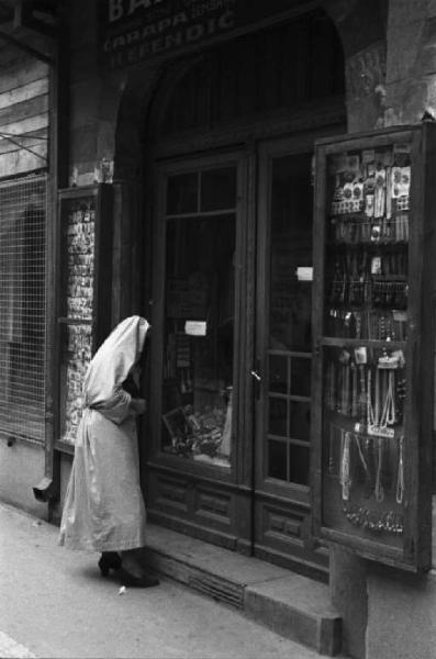 Viaggio in Jugoslavia. Sarajevo: una donna osserva le vetrina di una drogheria nella piazza della cattedrale