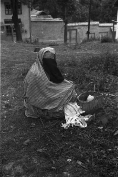 Viaggio in Jugoslavia. Sarajevo: donna bosniaca in costume tradizionale seduta in un campo