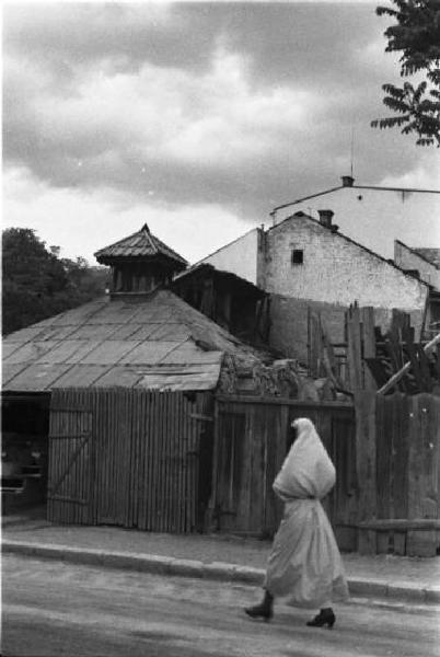 Viaggio in Jugoslavia. Sarajevo: scorcio di una zona residenziale - in primo piano una donna bosniaca in costume locale