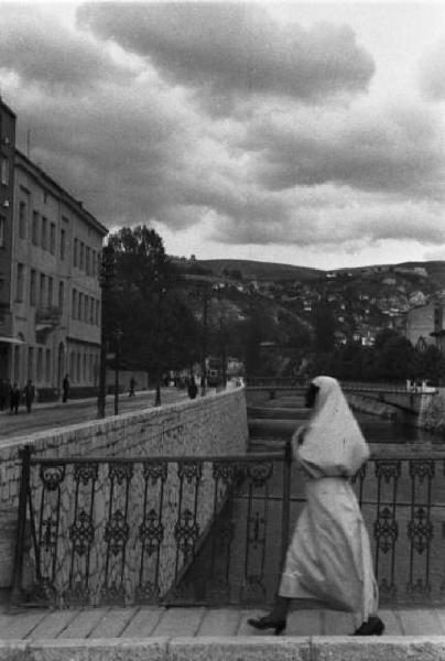 Viaggio in Jugoslavia. Sarajevo: scorcio di un quartiere residenziale con una donna bosniaca in costumi locali