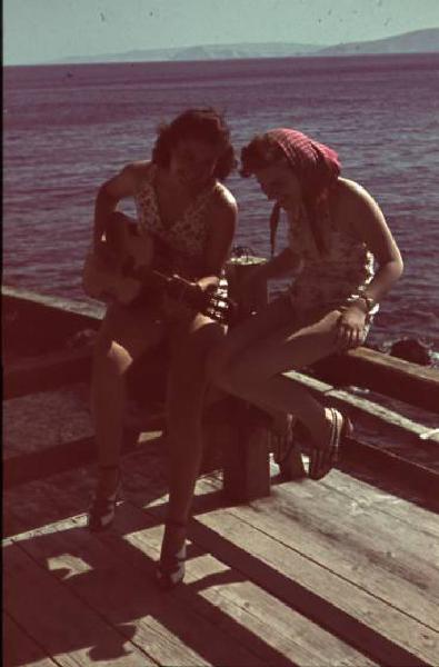 Viaggio in Jugoslavia. Senj (Segni): coppia di giovani ragazze suonano la chitarra sul lungomare